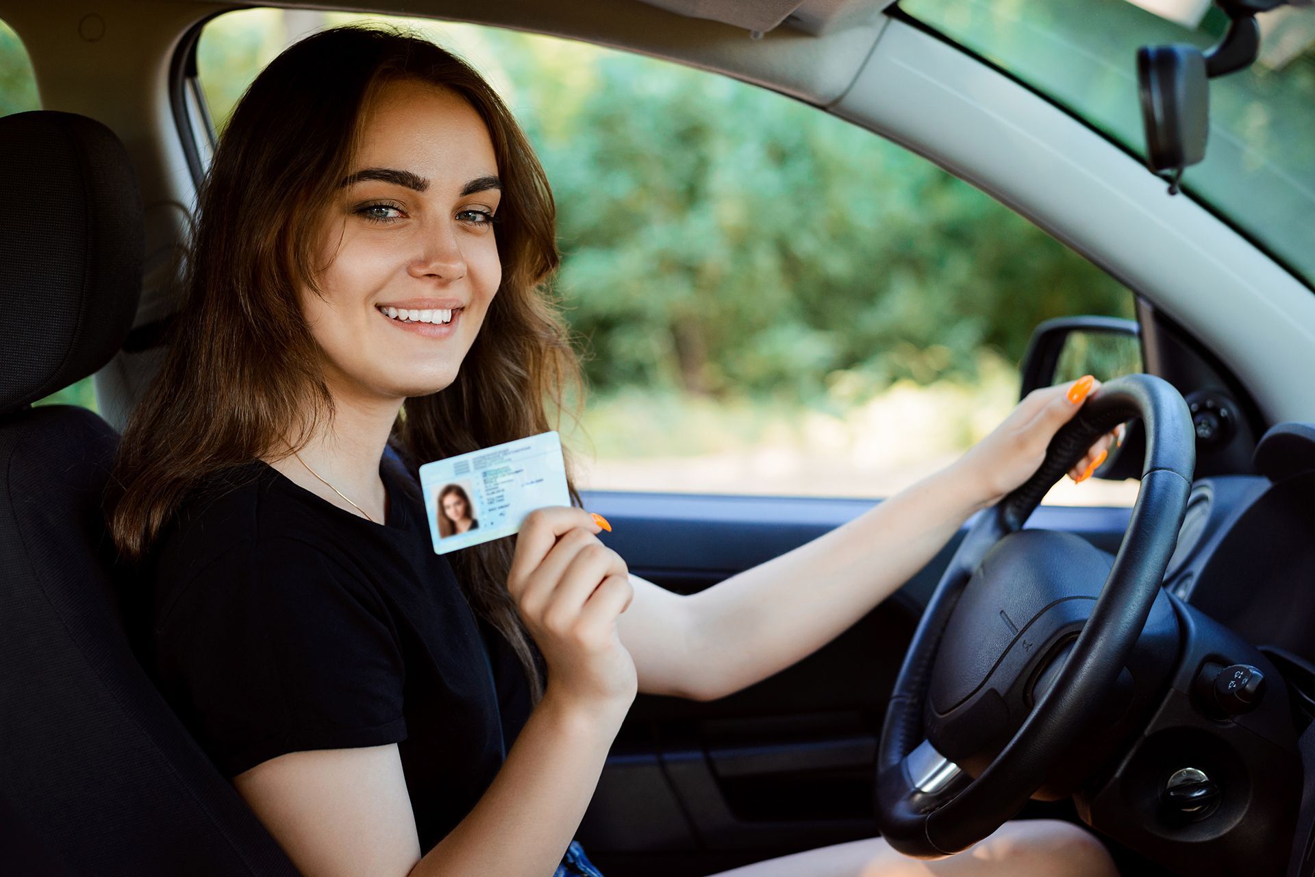 A woman is sitting in a car holding a driving license.