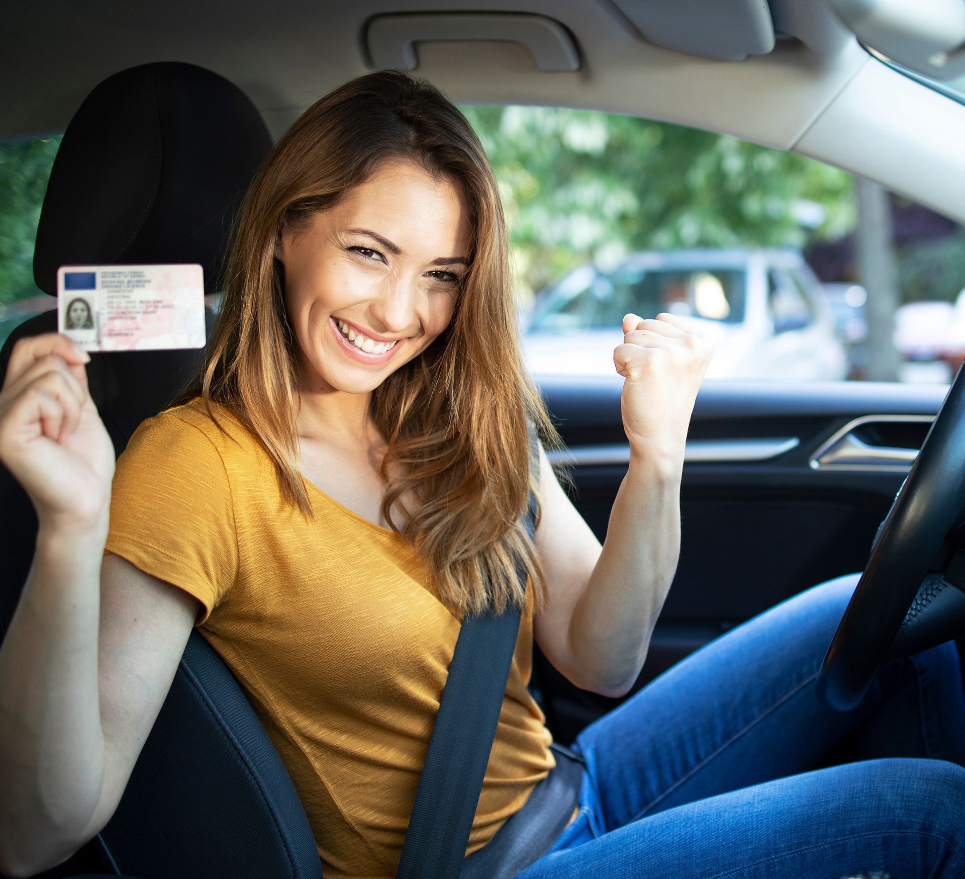A woman is sitting in a car holding a drivers license