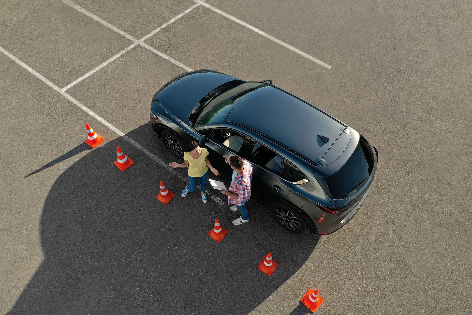 A couple of people are standing next to a car in a parking lot.
