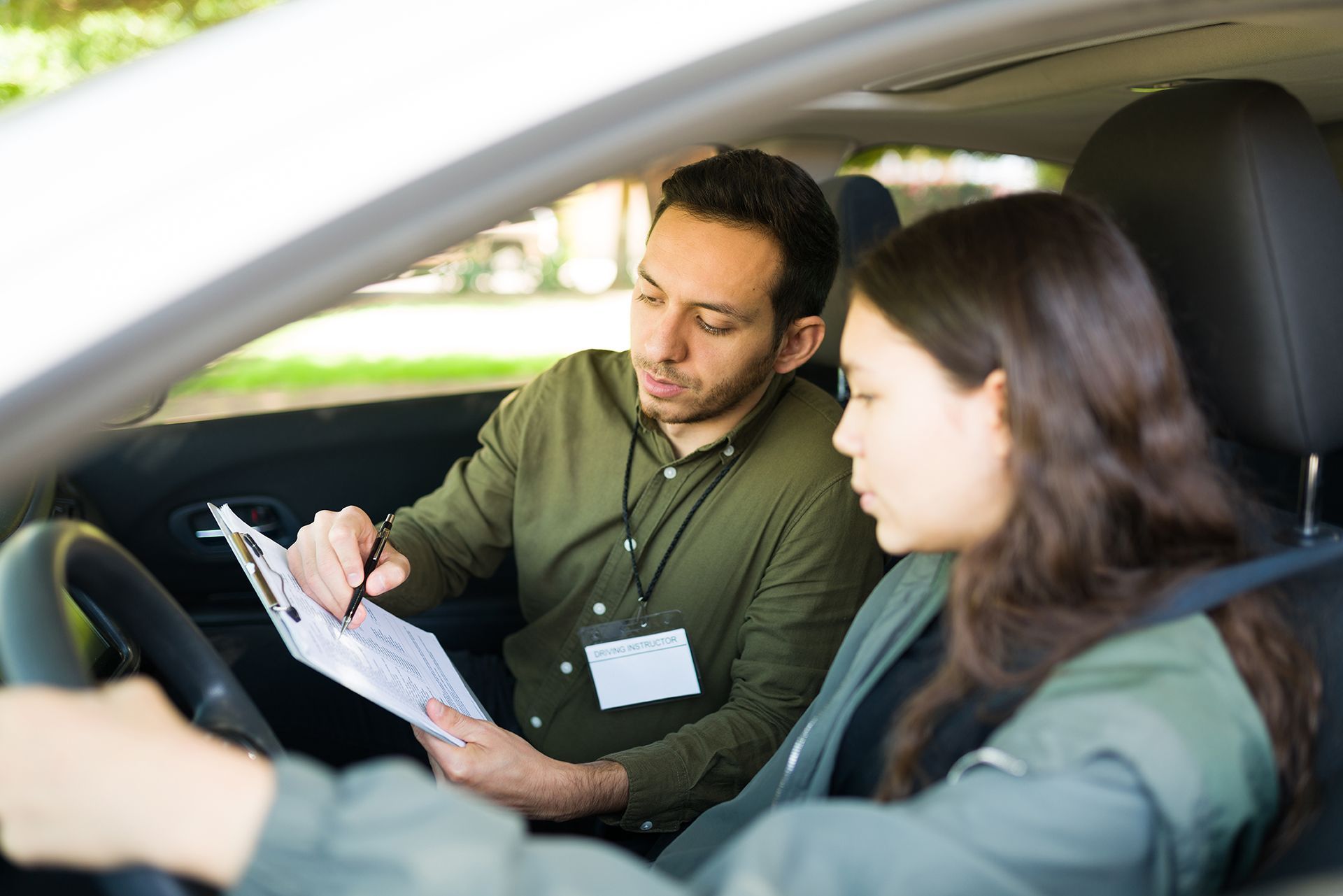 A man is teaching a woman how to drive a car.