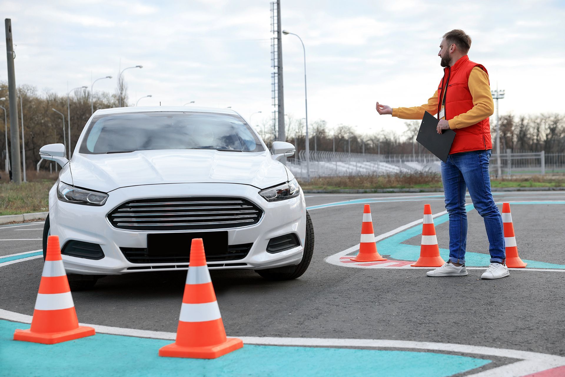 A man is standing next to a white car in a parking lot.