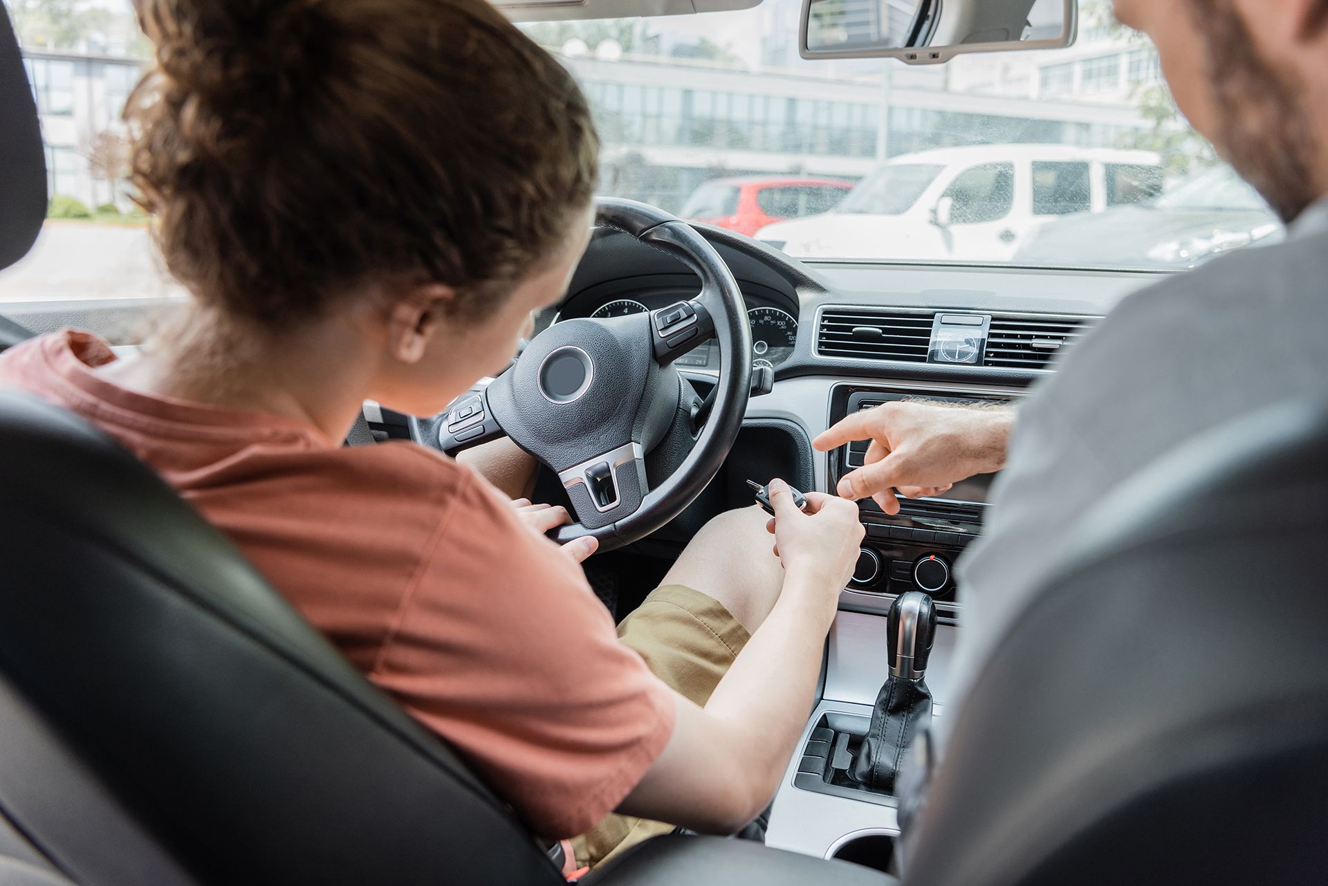 A man is teaching a woman how to drive a car.