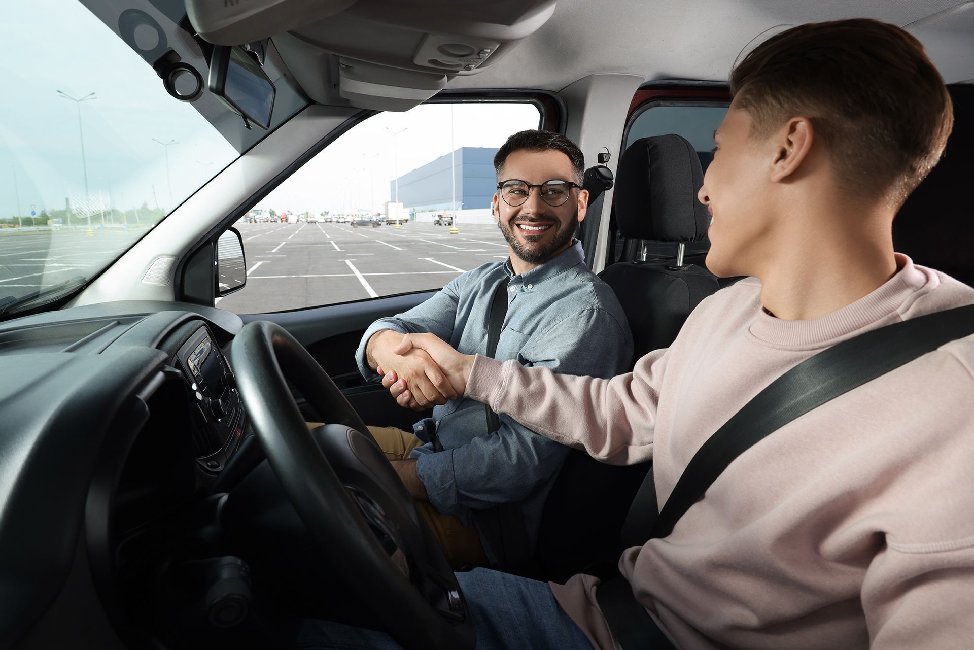 A man is shaking hands with another man in a car.