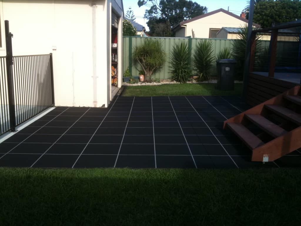 A backyard with a black tiled patio and stairs