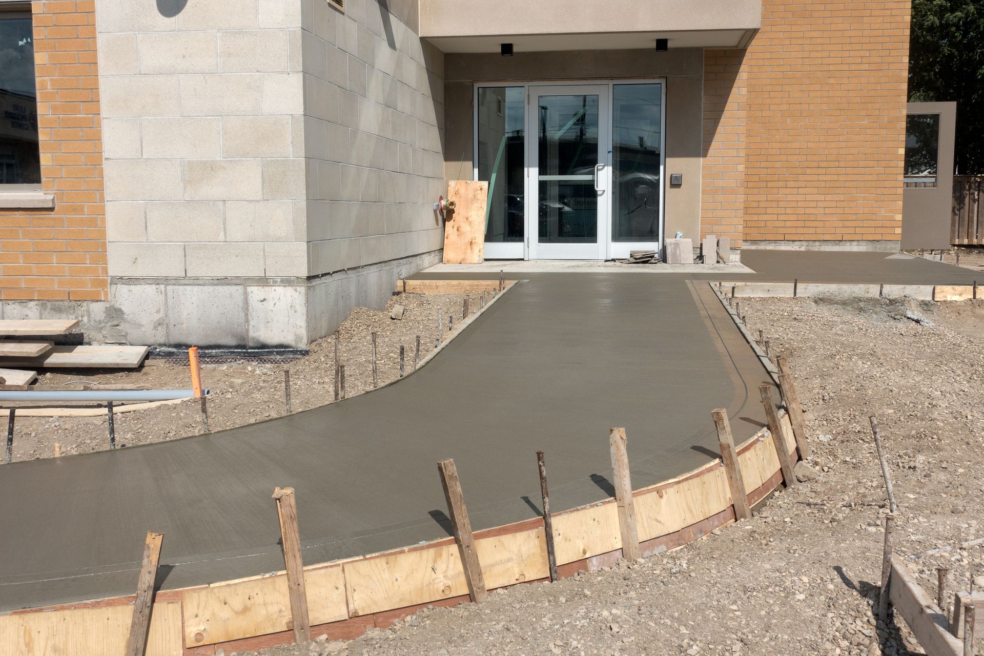 A freshly poured cement sidewalk leading into a new building. A freshly poured cement sidewalk leading into a new building.