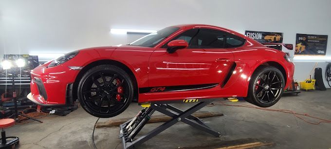 a red sports car is sitting on top of a lift in a garage .