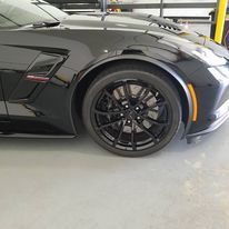A black sports car is parked in a garage.