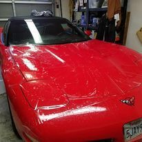 A red corvette is parked in a garage.