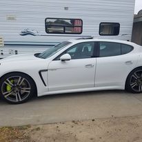 A white car is parked in front of a trailer.