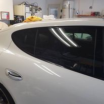 A white car is parked in a garage with a yellow towel on the roof.