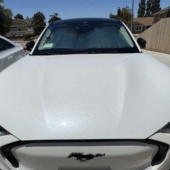 A white ford mustang electric car is parked in a driveway.