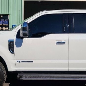 A white ford truck is parked in front of a building.