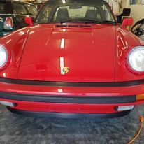 A red porsche 911 is parked in a garage.