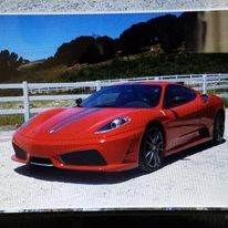 A red sports car is parked in front of a white fence.