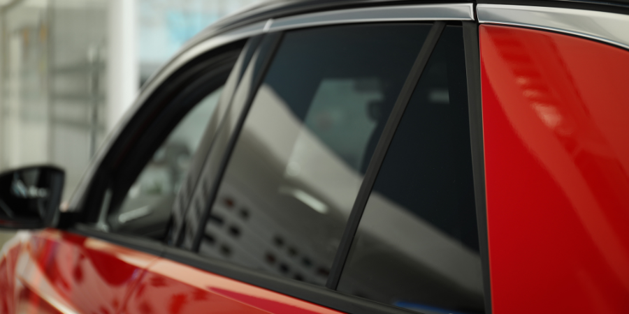 A red car with black windows is parked in a showroom.