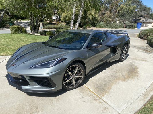 A gray sports car is parked in a driveway.