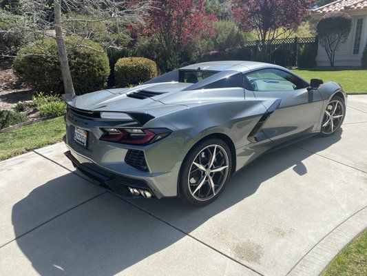 A silver sports car is parked on a driveway in front of a house.