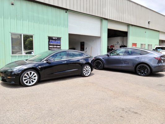Two tesla model 3 cars are parked in front of a building.