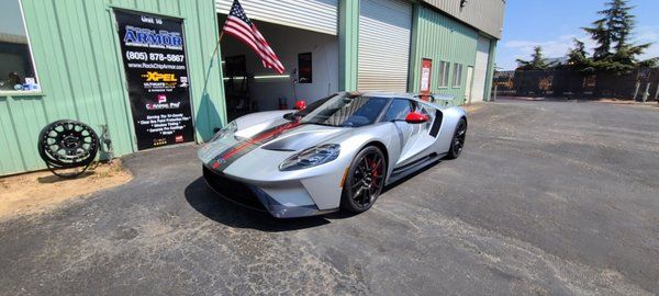 A silver ford gt is parked in front of a garage.