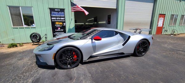 A silver ford gt is parked in front of a green building.