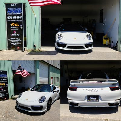A white porsche turbo is parked in front of a building