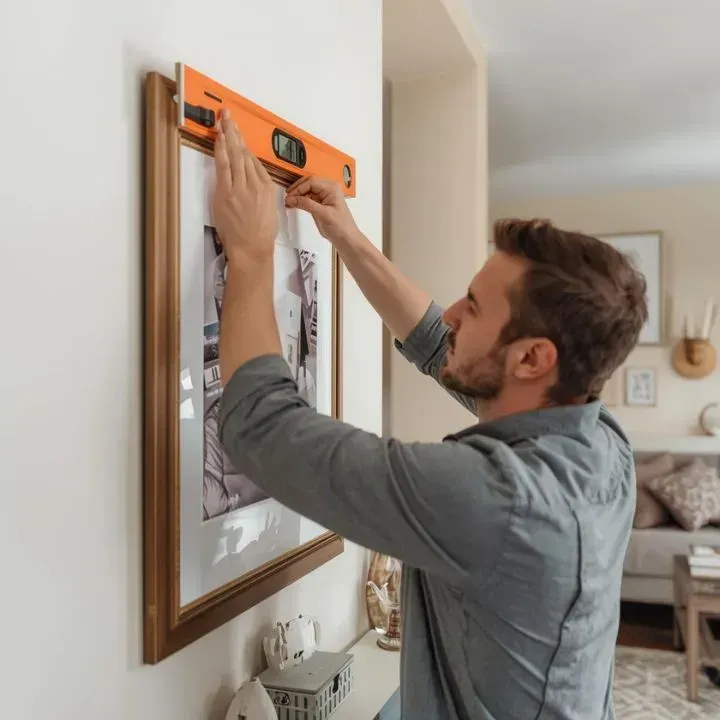 Mt. Juliet handyman using level to hang picture frame professionally in local home