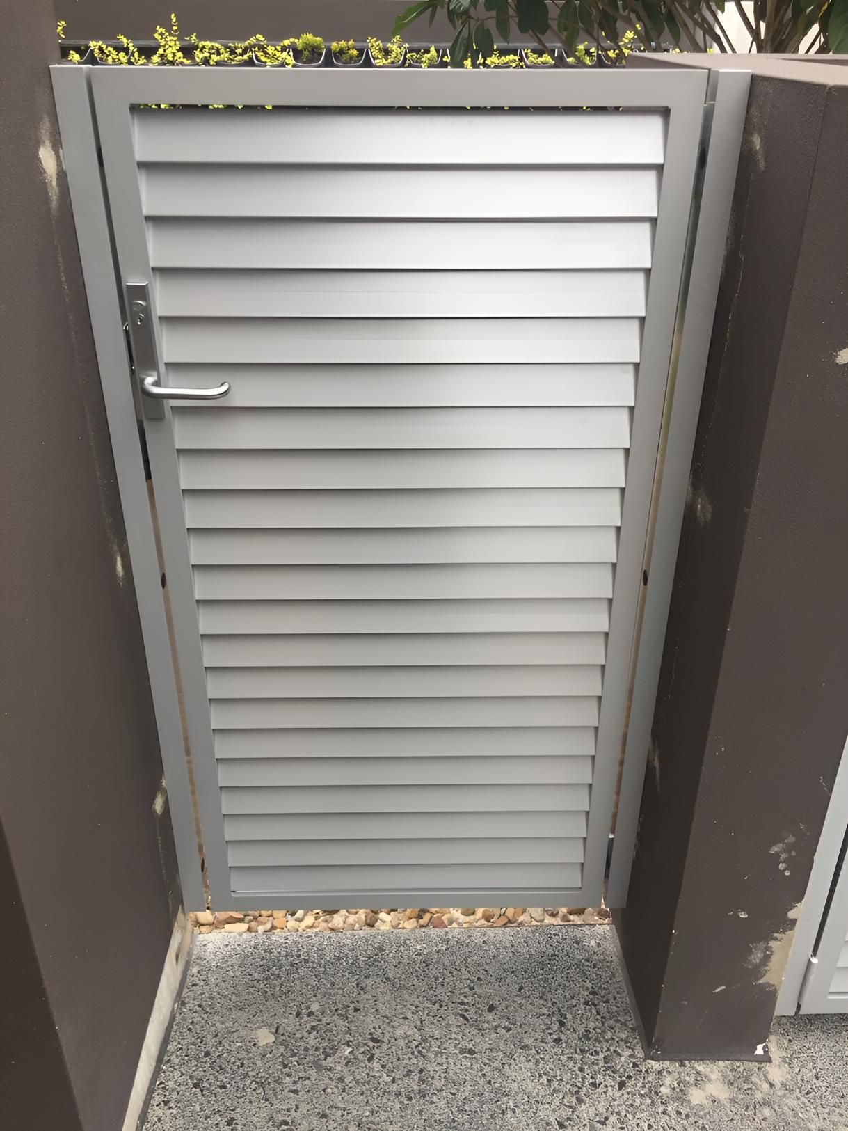 A Metal Gate With Shutters on It is Sitting Next to a Wall — Simmweld Metal Fabrication and Welding In South Murwillumbah, NSW