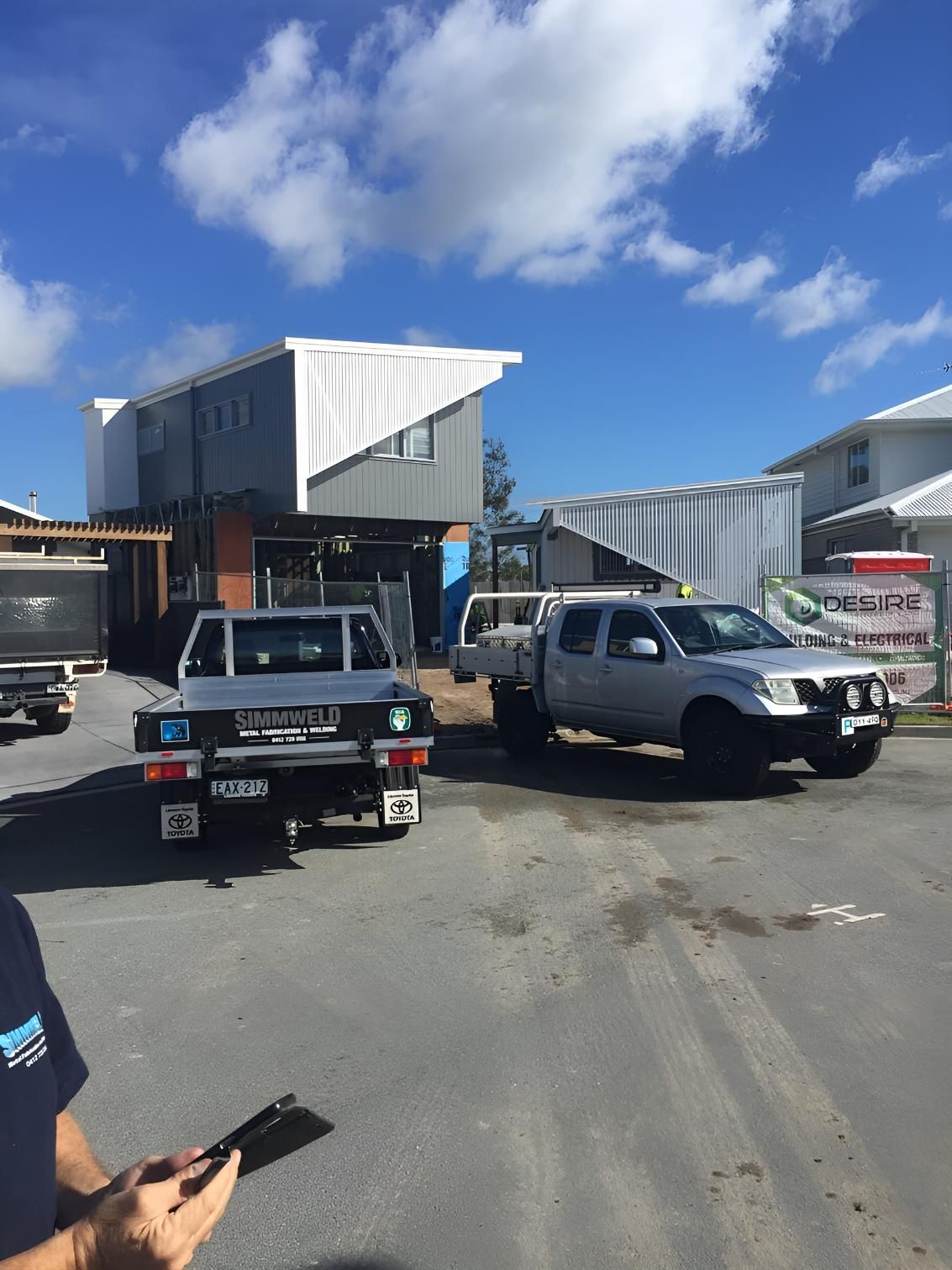 A Man is Standing in Front of a Building With Trucks Parked in Front  of It — Simmweld Metal Fabrication and Welding In South Murwillumbah, NSW