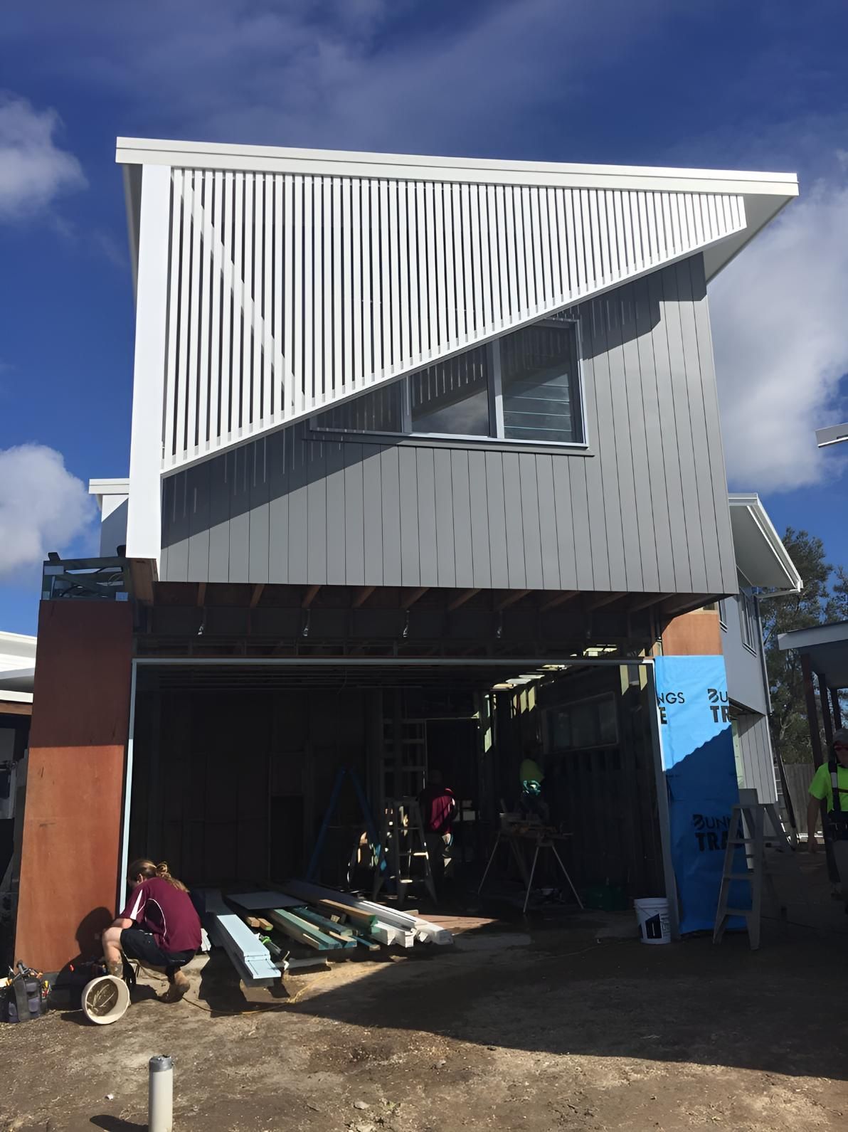 A Man is Kneeling in Front of a Building Under Construction — Simmweld Metal Fabrication and Welding In South Murwillumbah, NSW