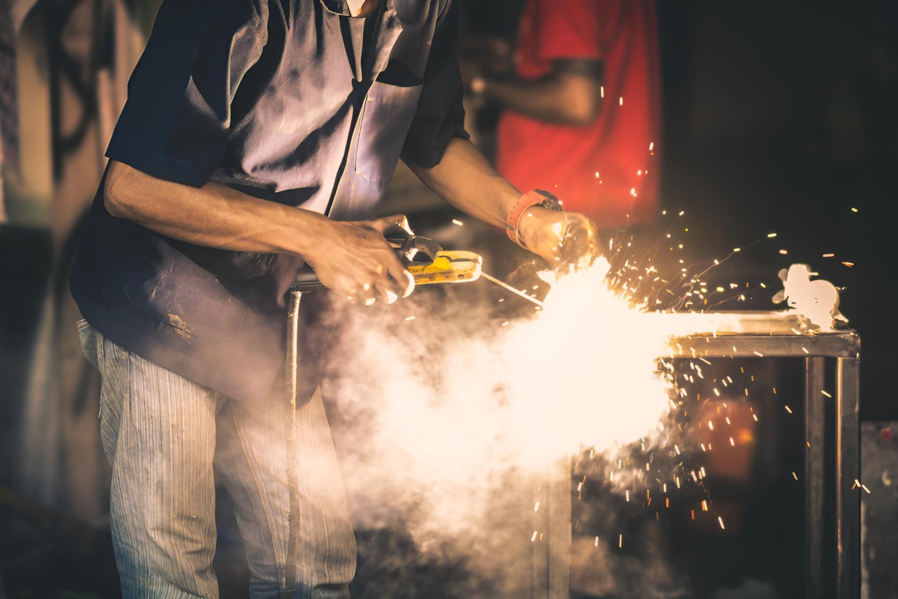 Man is Welding a Piece of Metal — Simmweld Metal Fabrication and Welding In Tweed Heads, NSW