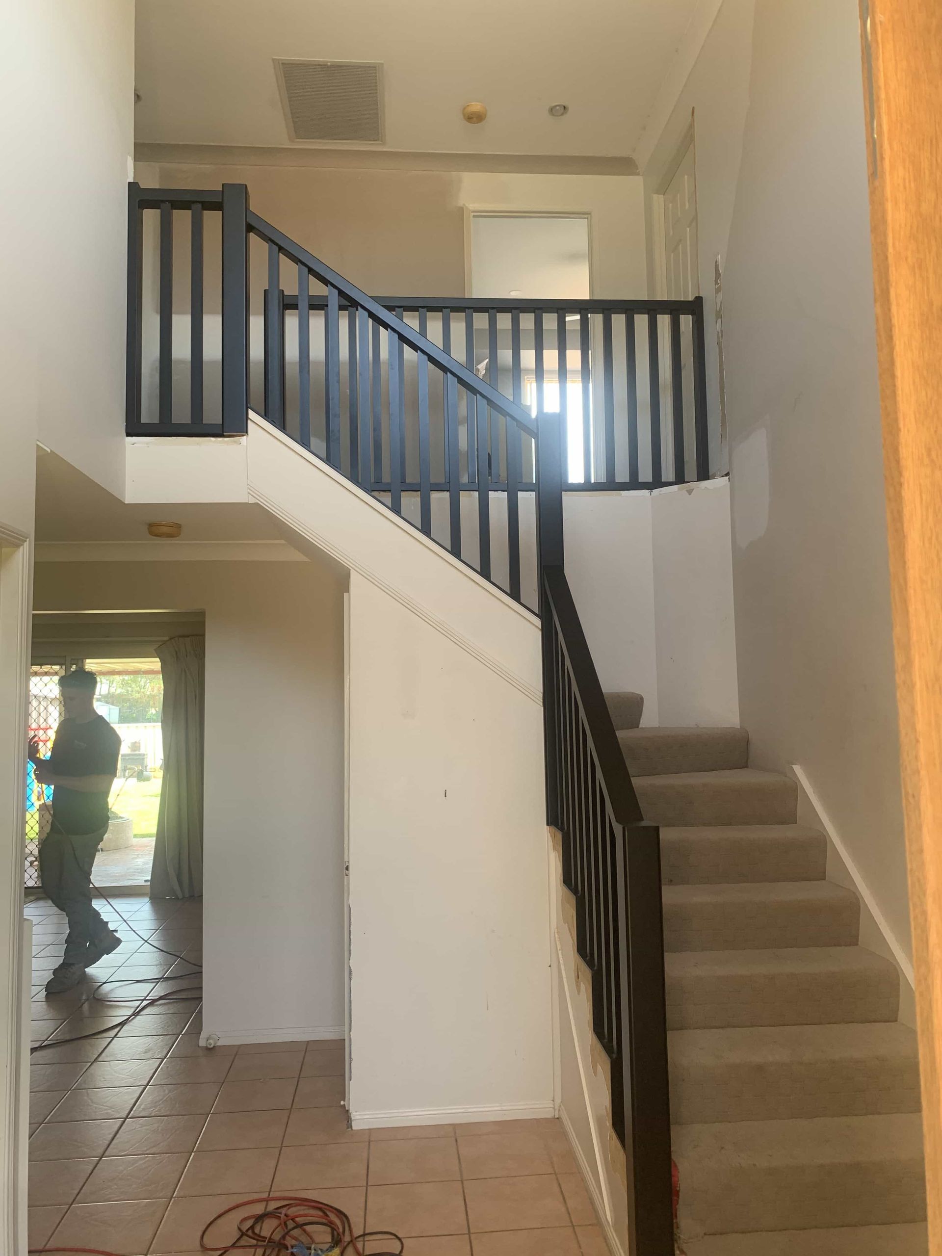 A man is walking down a set of stairs in a house — Simmweld Metal Fabrication and Welding In Banora Point, NSW