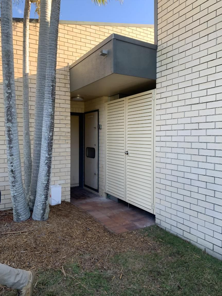 A White Brick Building With a Door and a Fence in Front of It — Simmweld Metal Fabrication and Welding In South Murwillumbah, NSW