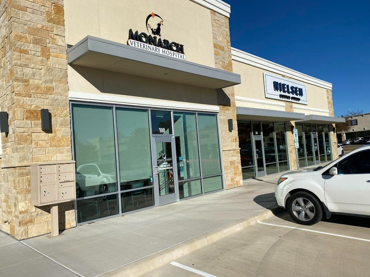 Exterior of a strip mall with two businesses, Monarch Barber Shop and Kilted Barber, on a sunny day.
