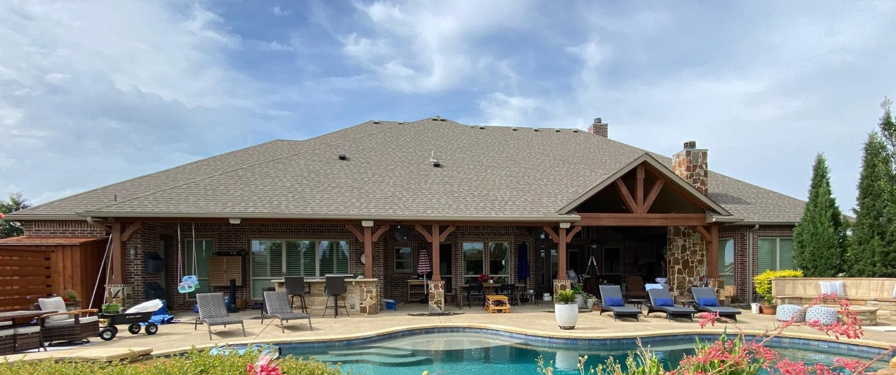 Large house with pool and outdoor seating under a cloudy sky.