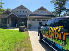 A house with a pressure washing truck in front. Green grass and blue sky. The truck says