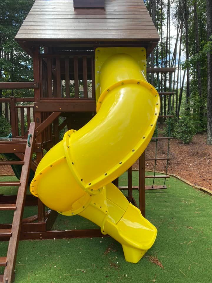 Bright yellow playground slide near cleaned play area maintained with power washing services