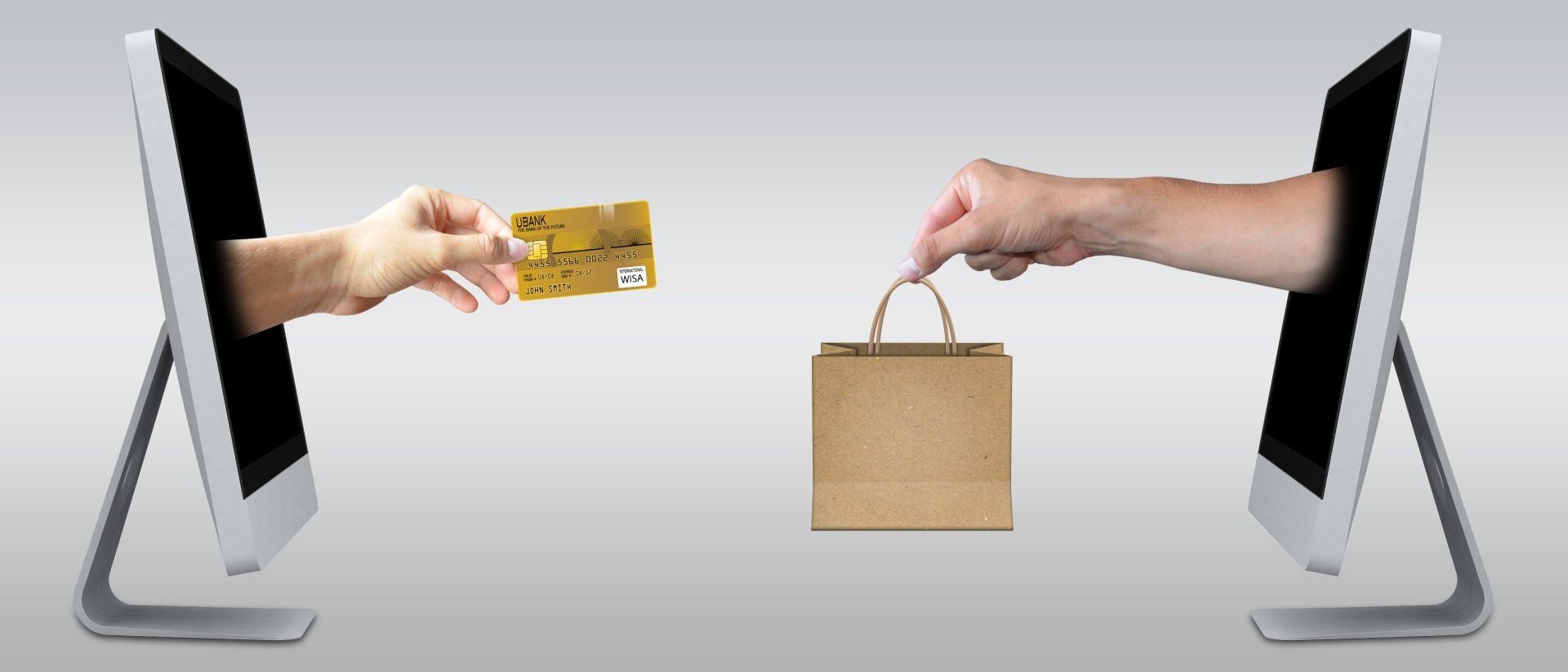 one hand reaching out of computer with credit card to other hand carrying shopping bag from second computer