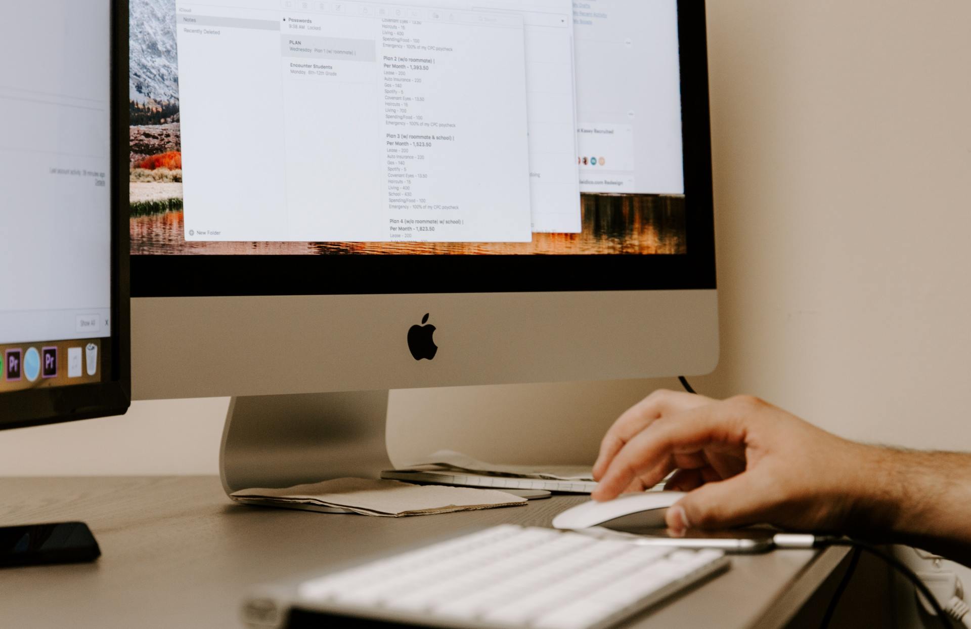 person's hand using computer mouse beside mac desktop