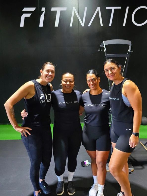 Four women posing for a picture in front of a sign that says fitnatic