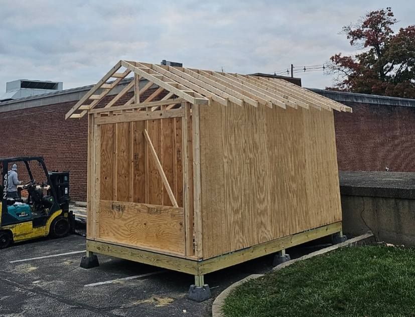 A wooden structure under construction. A yellow forklift sits on the left.