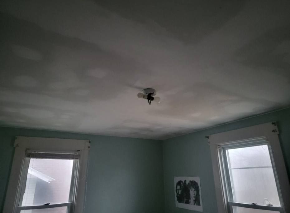 A bedroom ceiling with a light fixture and two windows below. Walls are light blue.