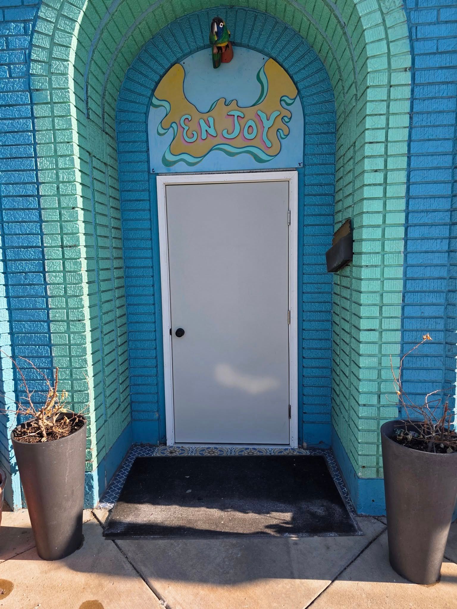 Entrance with turquoise arched brickwork, a white door, and 