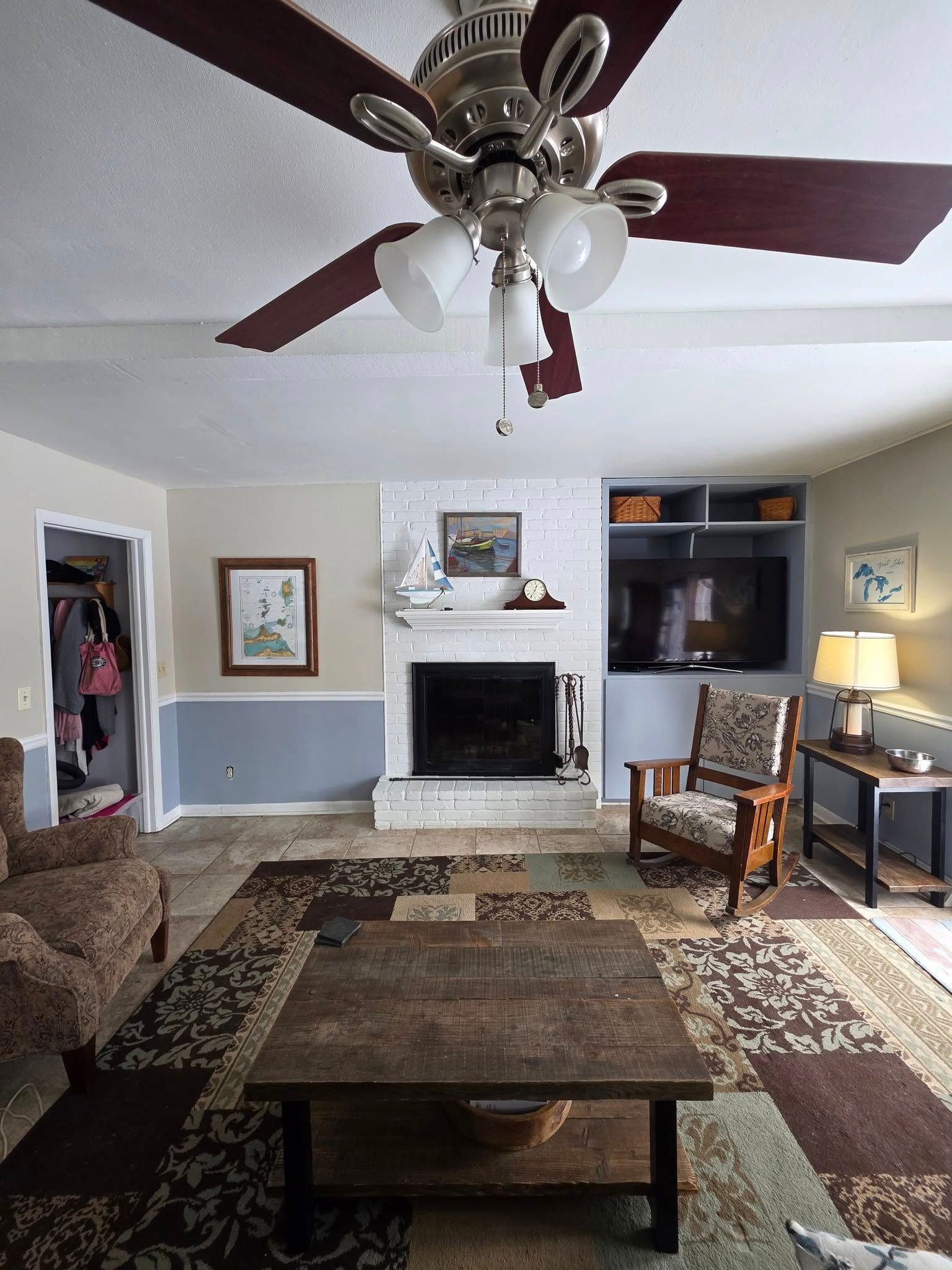 Living room with a fireplace, TV, furniture, and a ceiling fan.