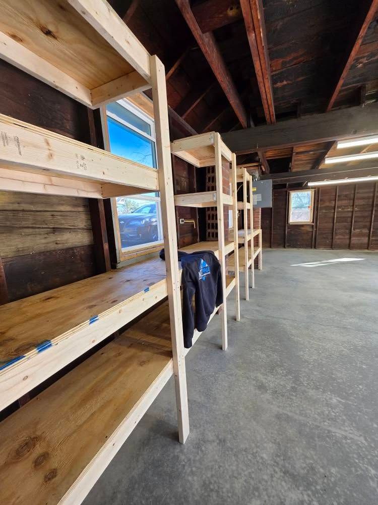 Wooden shelves built inside a garage with a window, the ceiling is made of wood.