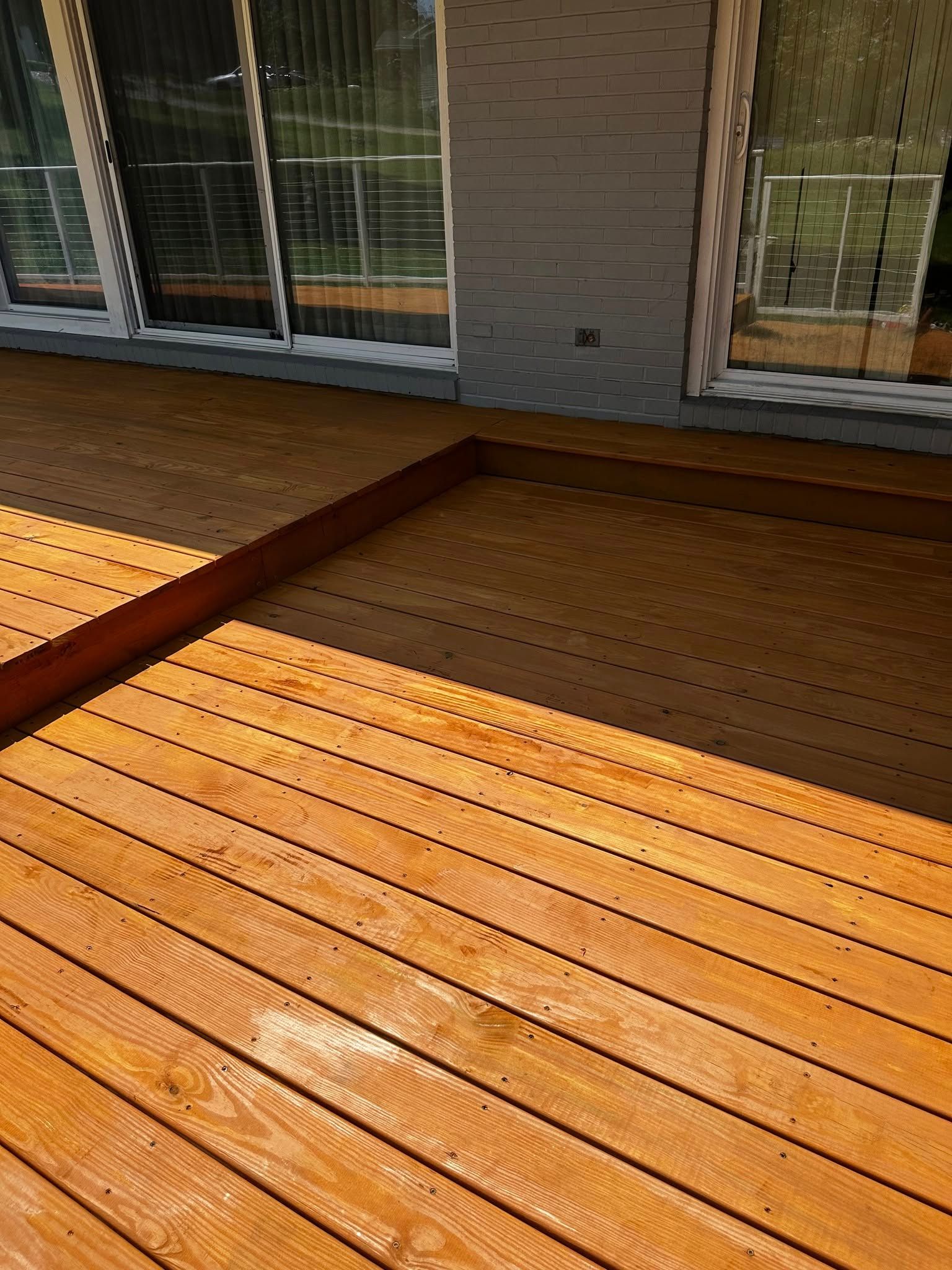 Wooden deck with a light stain, next to a house with windows.