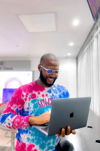 A man in a tie dye shirt is using a laptop computer.