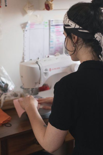 A woman in a black shirt is using a sewing machine