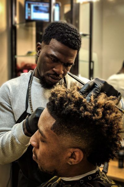 A man is getting his hair cut by a barber in a barber shop.