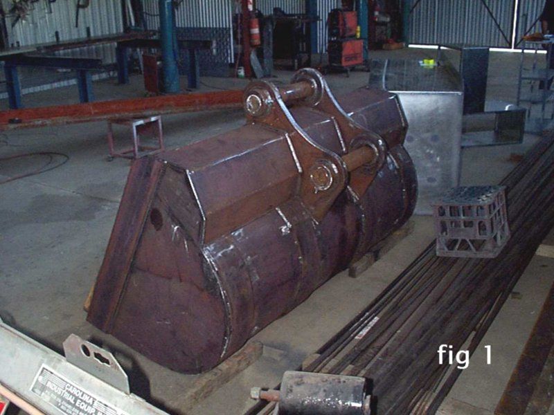 A large metal bucket is sitting in a warehouse with the words fig 1 below it