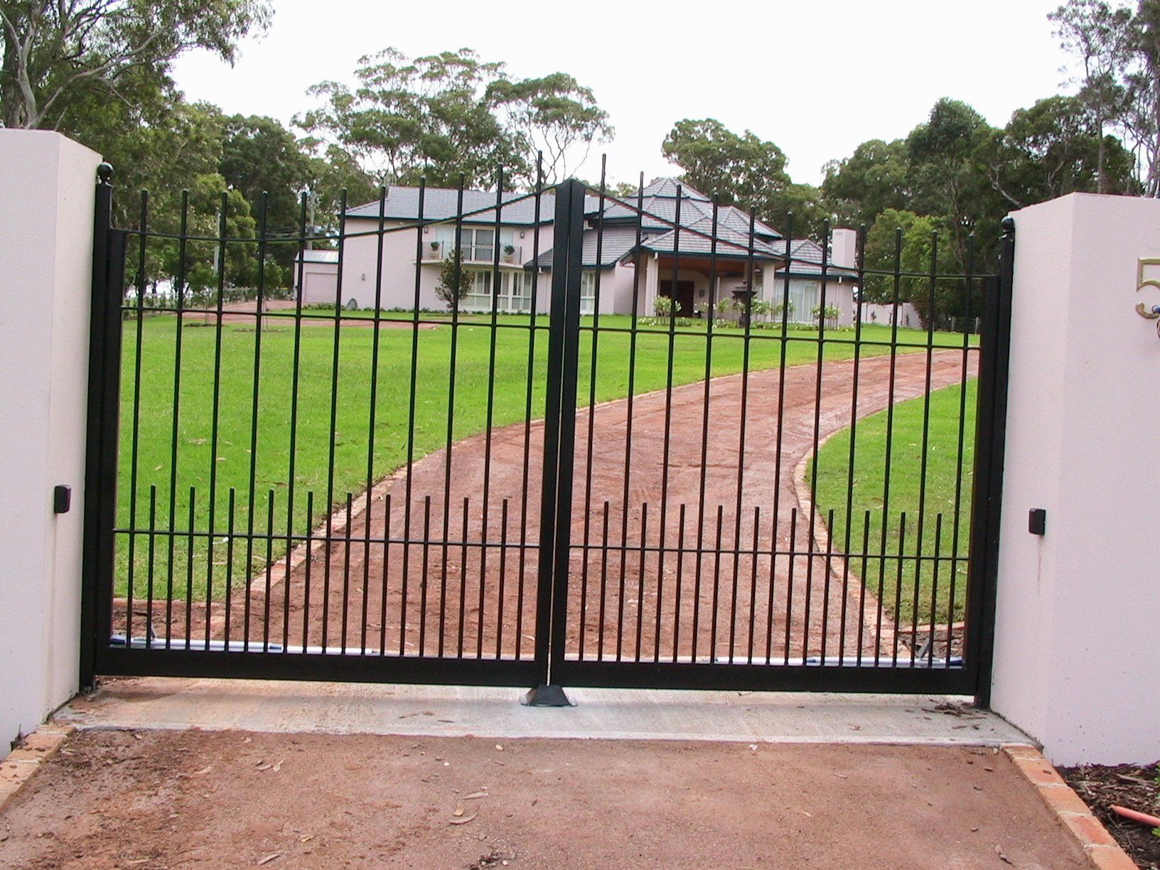 A large house is behind a gate that has the number 5 on it